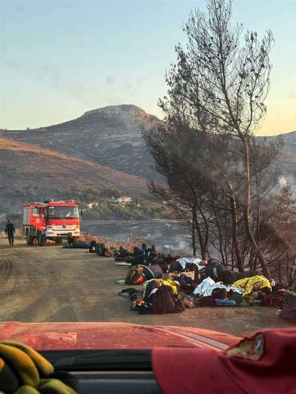 Εξαντλημένοι πυροσβέστες ξαπλώνουν στο χώμα για να ξεκουραστούν